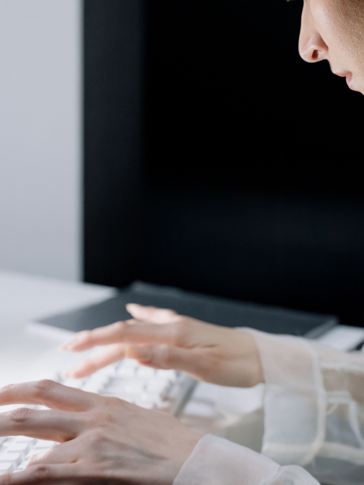 A person typing at a keyboard, screen in the background.