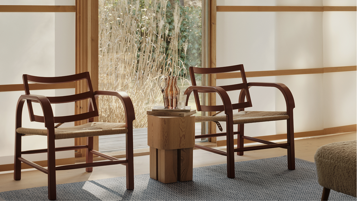 Two Kasthall lounge chairs beside a wooden side table in a living room.